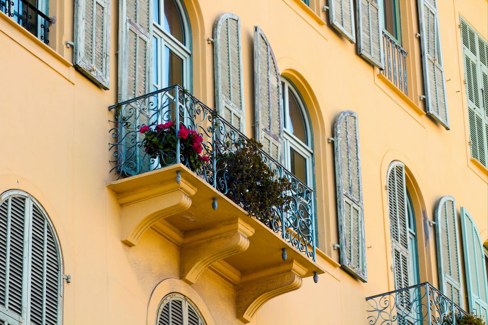 Person gießt Pflanzen auf einem Balkon, Wasser läuft zur Vorderkante